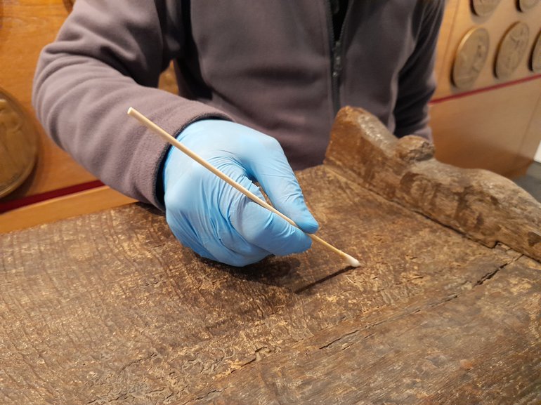 A conservator working on the Grain Ark with a cotton wool swab dipped in Vulpex.