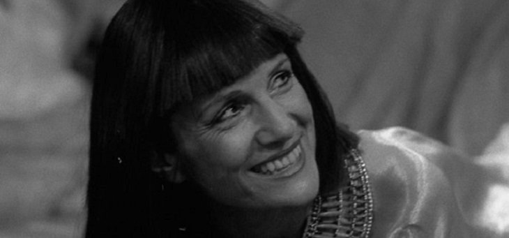 Cleopatra (dark, straight hair falling either side of her face) is smiling lovingly at someone out of sight.