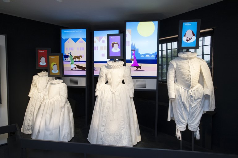 Meet the Shakespeares in our innovative new exhibition centre. The clothes, a lot of which are white, are two girls' dresses, a lady's dress, and a gentleman's dress, with doublet and shin-length slops with tassels at the bottom. They are shown with ruffs, so would be the clothing of gentry.