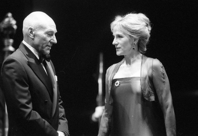 Hamlet, Courtyard Theatre, 2008. In modern dress Gertrude (on the right) is in conversation with Polonius. He wears a dark suit, she a tight dress with a straight top above the bust and a light garment over her arms and shoulders.