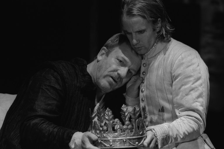 Royal Shakespeare Company, 2007. Henry IV leans against his son's shoulder; Hal rests his cheek against his father's head. Each has one hand on the crown in the centre of the foreground. Both look sorrowful but calm.