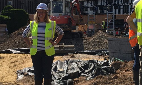 Julie Crawshaw, wearing a high-viz vest and a helmet, is seen standing on  the building site.