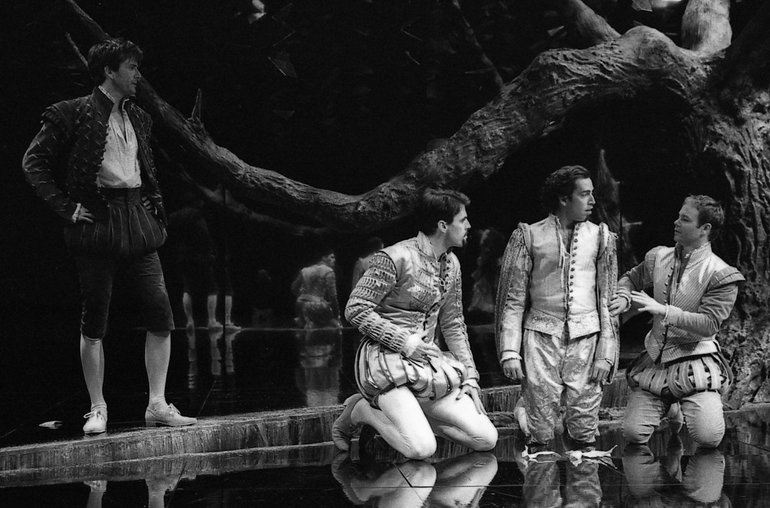 Three men in courtly Elizabethan clothes kneel as they argue. To their right stands a peasant figure in black. In the background is a thick twisted tree branch.