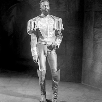 Macduff is photographed wearing knee-length boots, very tight hose, and a jacket which has huge epaulettes with tassels hanging  half-way to his elbows.