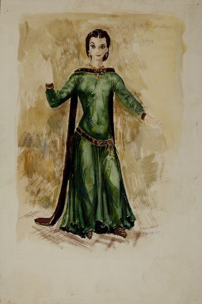 Macbeth Costume for Vivien Leigh as Lady Macbeth, 1955. A green, long mediaeval dress with tight full-length sleeves, a belt with an ornate gold buckle, and a black velvet trim round the neck which extends to the ground behind her on her right.
