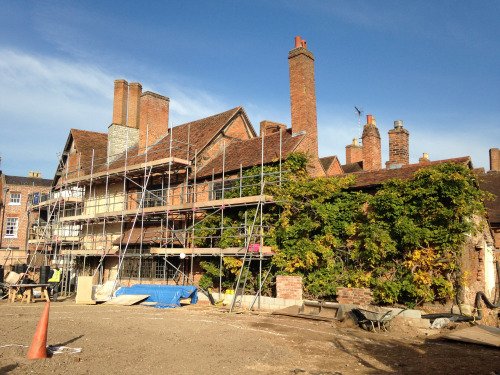 Nash's House with scaffolding, seen from the site of New Place. The scaffolding extends over two thirds of the house; part of this, and the remaining (lower) third is covered with ivy.