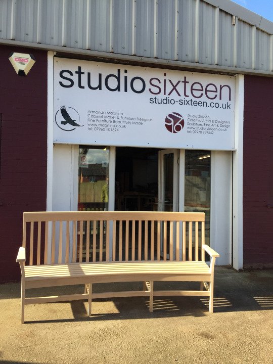 Outside the workshop one of the benches, in light-coloured wood, is shown with its plank seating and the many thin vertical laths at the back.