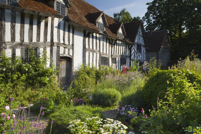 Front garden of Palmer's Farm, full of shrubs and  flowers,  with Palmer's farmhouse in the background