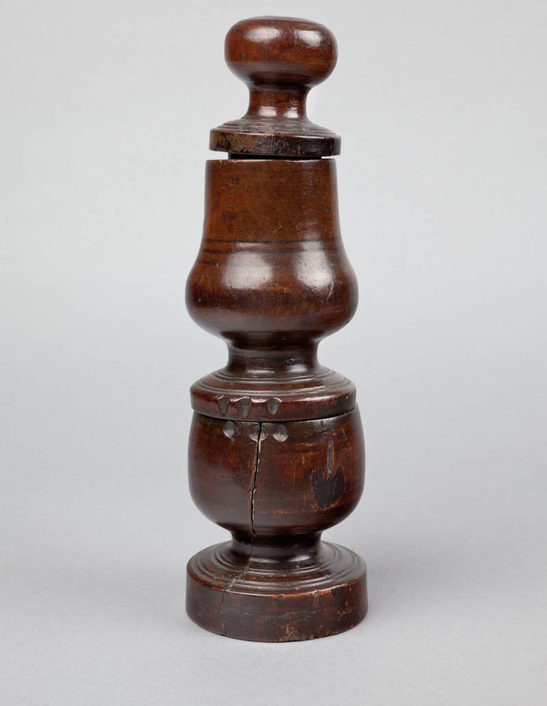 A dark wooden Spice Grinder: circular base short narrow stem, cup shape to receive ground spice, lid and short narrow stem, spice-holder with straight sides but curving out at base, lid and grinder knob.