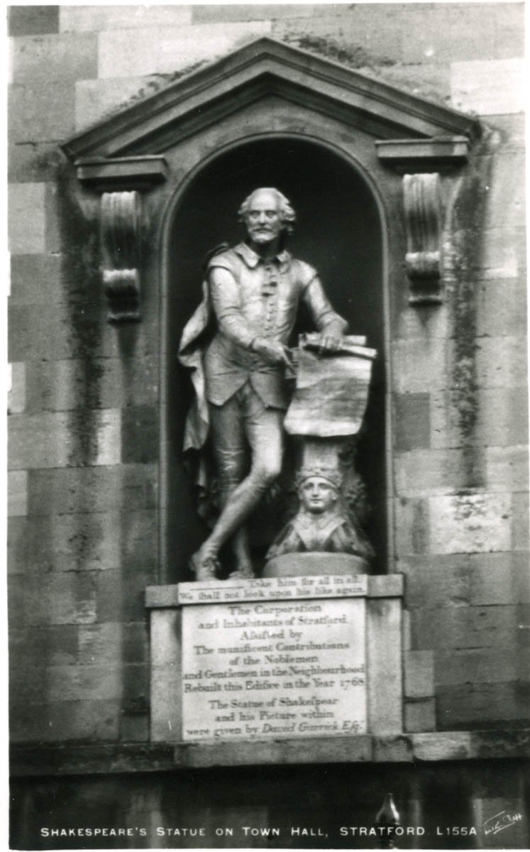 The statue shows Shakespeare leaning on a pillar, one leg crossed over the other; he holds a manuscript which he is unrolling in front of the pillar. It stands on a plinth bearing and inscription.