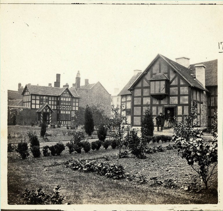 The image shows the rear of the birthplace and a path running towards it, newly-planted with shrubs and some flowers on the borders; the rest of the garden is bare.