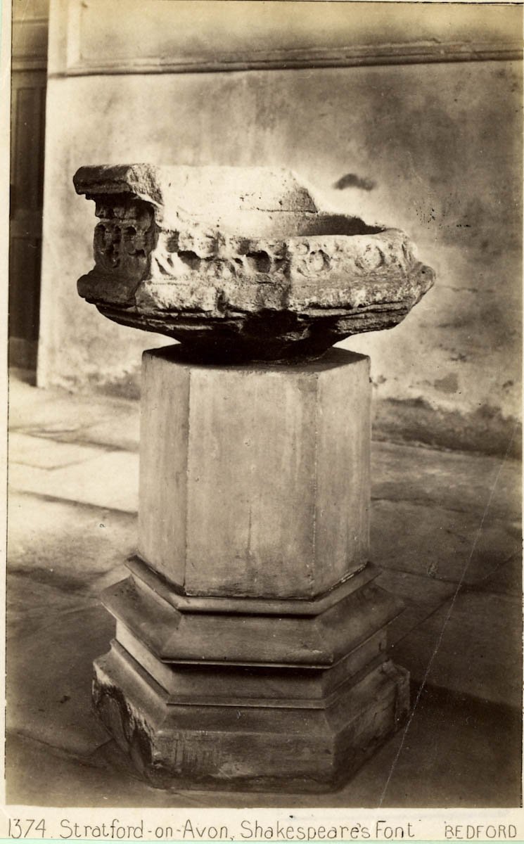 The stone font is on a hexagonal pedestal with a decorated base. The font itself is shaped like a hexagonal chair,, higher at the rear three sides of the hexagon, and the stone is carved all round with a geometrical pattern.