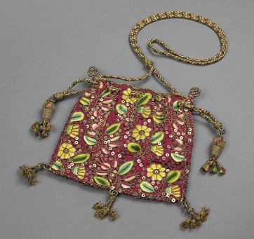 A sweet bag that dates from the late 1500s. It has a red background and is finely decorated with yellow flowers and green leaves.