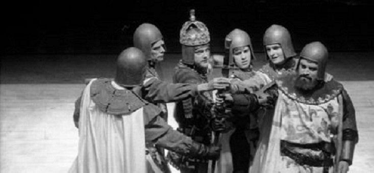 Six armed men stand in a close semi-circle, their right-hands joined in the centre. The bearded man at the end on the right wears a surcoat with the French arms; the man third from the left has a crown over his helmet.