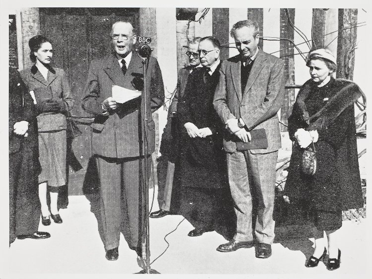 Hall's Croft Opening 1951. A moustached man in a check suit makes a speech, with a BBC microphone in front of him. On his left are three men in suits and a lady in a coat with a fur collar; on the speaker's right is anther lady in a formal skirt suit.