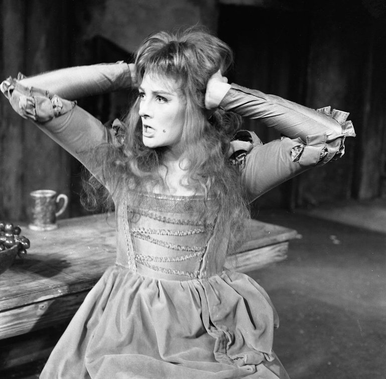 Taming of the Shrew Royal Shakespeare Company, 1962. Katherine, her hair loose and wild and the laces of the bodice of her gown loosened, holds her hands to her head as she snarls (presumably at Petruchio).