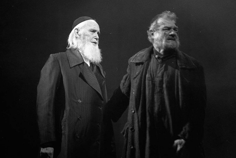 The Merchant of Venice Royal Shakespeare Company, 1997. Two men, one with a white beard and a skull-cap, the other middle-aged with a short beard and slightly wild hair, stand together looking to our right.
